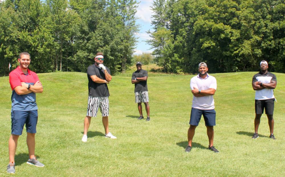 five alumni posing together on the golf course